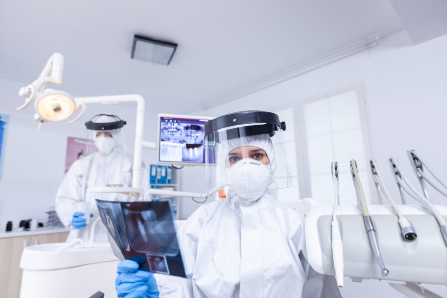 Dois dentistas atuando juntos em uma clínica odontológica integrada, avaliando os exames de raio-x de um paciente.