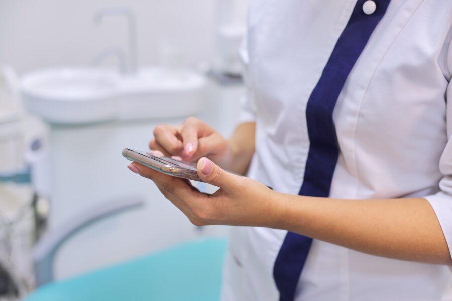 Profissional de saúde usando um smartphone em um ambiente clínico, acessando o aplicativo receita saúde.