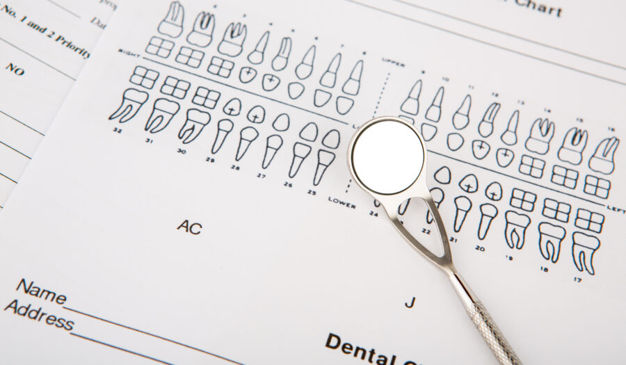 Imagem de um odontograma anatômico com um espelho dental ao lado, destacando a organização dos dentes para avaliação odontológica.