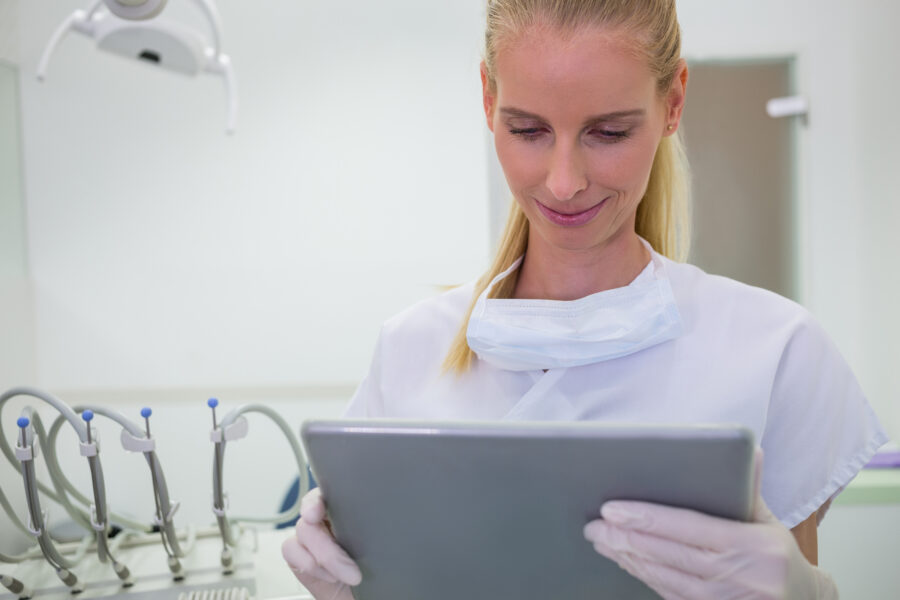 Profissional de odontologia utilizando um tablet para visualizar um odontograma digital, destacando a modernidade na prática dental.