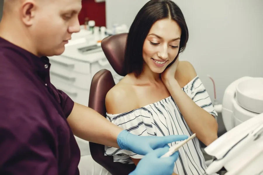 Imagem que retrata um dentista atendendo uma paciente. O foco é na experiência do paciente durante a consulta odontológica, com um sorriso de satisfação.
